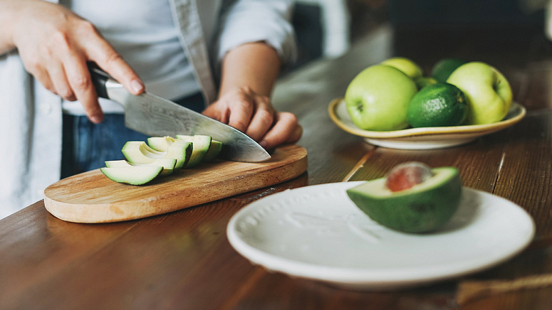 Девушка нарезает авокадо фото